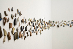 Tumbled glazed stoneware pottery shards glued to wall at eye-level in a loose mosaic pattern.