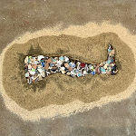 Impression of leg in wet sand filled with tumbled glazed stoneware pottery shards.