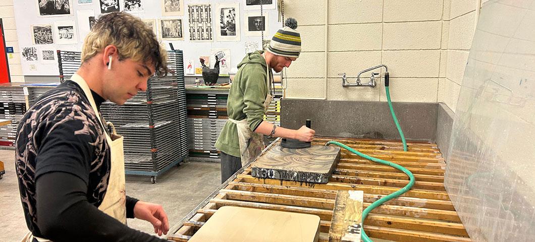 Two students prepare their stones for lithography printing. 