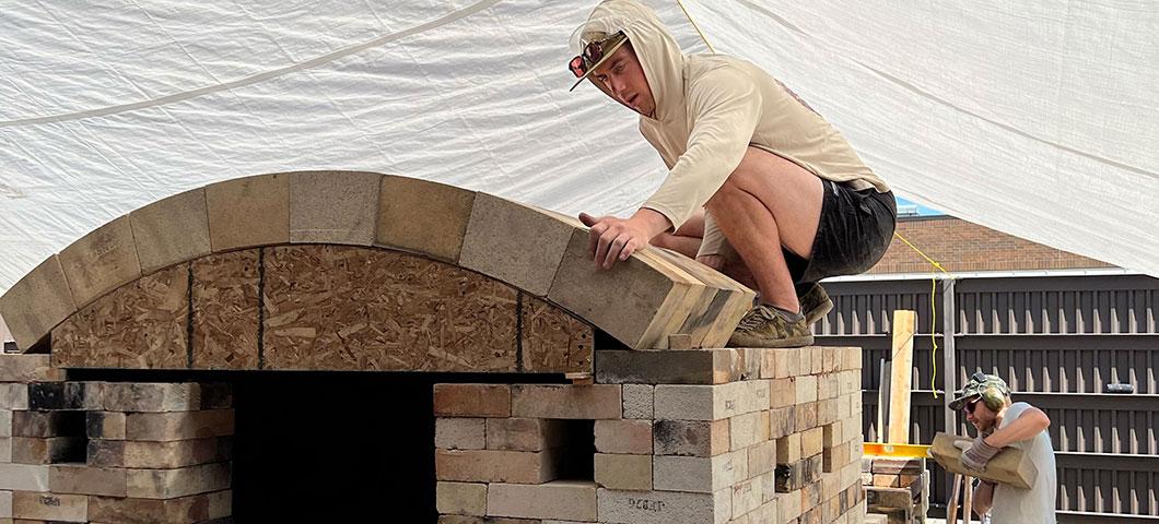 A student builds a wood fire kiln. 